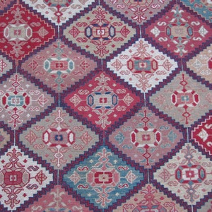 May include: A close-up of a patterned rug with a repeating diamond design. The rug features a variety of colors, including red, blue, and white.