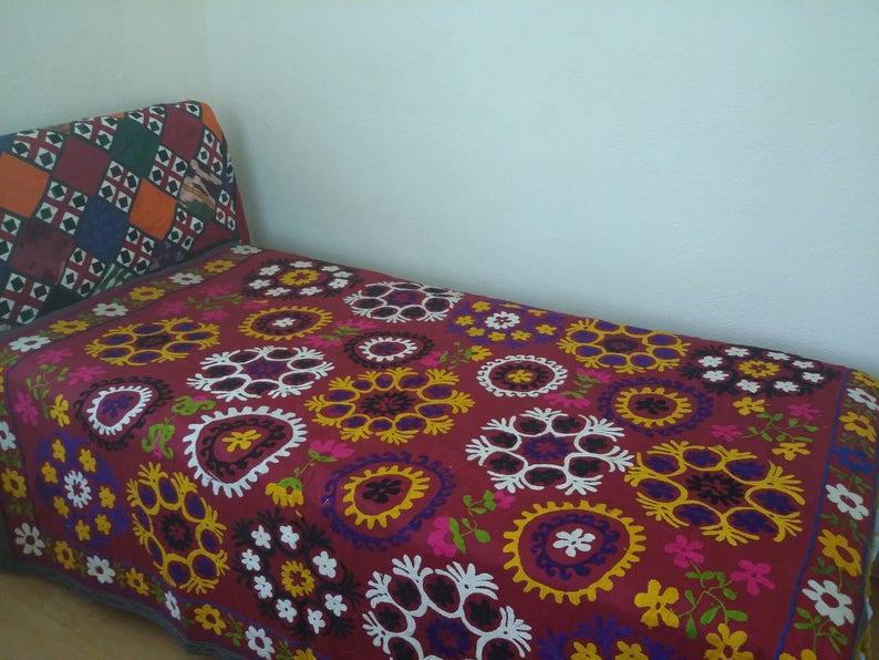 Puede incluir: Una manta de tiro bordada en rojo, blanco y azul con un patr&oacute;n floral. La manta est&aacute; hecha de algod&oacute;n y es perfecta para agregar un toque de color y estilo a cualquier habitaci&oacute;n.