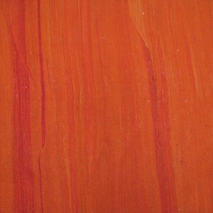 K&ouml;nnte beinhalten: Nahaufnahme einer strukturierten orangen Oberfl&auml;che mit roten Farbstreifen. Die Oberfl&auml;che hat eine leicht raue Textur.