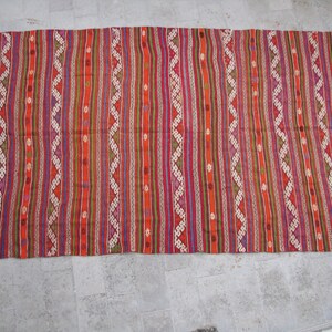 May include: A colorful striped rug with a geometric pattern. The rug is made of wool and has a fringe on the ends.