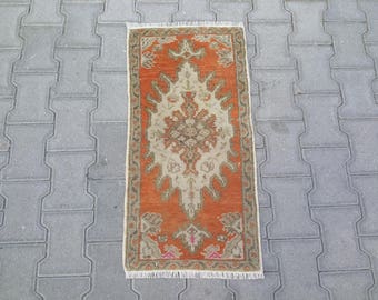 Könnte beinhalten: Ein kleiner, rechteckiger Teppich mit orangefarbenem Hintergrund und einem cremefarbenen Blumenmuster. Der Teppich hat einen Fransenrand.