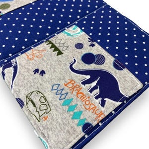 K&ouml;nnte beinhalten: Eine blaue und wei&szlig;e Stoffbrieftasche mit Polka Dots und einer grauen Tasche mit einem blauen Elefanten und dem Wort "Brachiosaurus". Die Brieftasche hat ein Dinosaurier-Thema mit anderen Dinosaurier-Illustrationen.