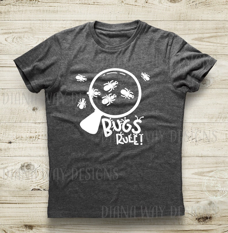 Puede incluir: Camiseta gris oscuro con un gr&aacute;fico blanco de insectos vistos a trav&eacute;s de una lupa. El texto "BUGS RULE!" est&aacute; debajo de la lupa. La camiseta es de cuello redondo.