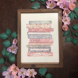 May include: A framed print of a stack of classic literature books, including Jane Eyre, Pride and Prejudice, Wuthering Heights, Emma, The Secret Garden, and Little Women. The books are illustrated in a watercolour style with a vintage aesthetic.