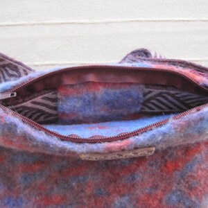 K&ouml;nnte beinhalten: Eine blaue und rote gemusterte Wollschultertasche mit Rei&szlig;verschluss. Die Tasche ist offen und das Innenfutter ist sichtbar.