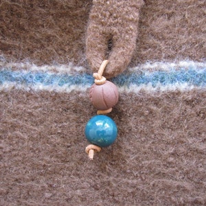 May include: A brown wool fabric with a blue and white stripe and a brown and blue bead necklace.