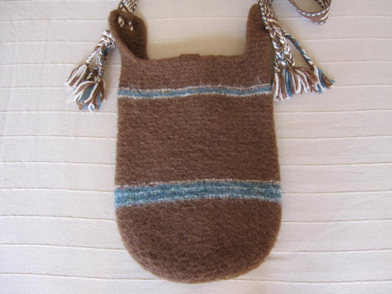 May include: A brown knitted bag with blue and white stripes and fringe details. The bag has a long strap and is made of a soft, textured material.