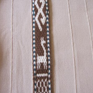 May include: A brown and white woven strap with a geometric pattern and a white silhouette of a llama or alpaca.