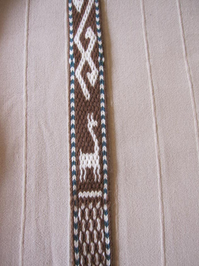 May include: A brown and white woven strap with a geometric pattern and a white silhouette of a llama or alpaca.