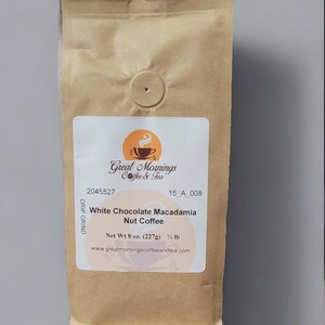 K&ouml;nnte beinhalten: Ein brauner Papierbeutel mit einem wei&szlig;en Etikett, auf dem "Great Mornings Coffee & Tea" und "White Chocolate Macadamia Nut Coffee" steht. Das Etikett enth&auml;lt auch den Text "Net Wt 8 oz. (227g) &frac12; lb" und "www.greatmorningscoffeeandtea.com".
