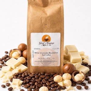 Great Mornings White Chocolate Macadamia Nut Coffee in a kraft paper bag on a white studio background, surrounded by roasted coffee beans, white chocolate pieces, and whole and shelled macadamia nuts.