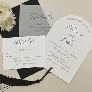 Puede incluir: Conjunto de invitaciones de boda con un sobre negro, una tarjeta RSVP blanca y una tarjeta blanca en forma de abanico con el texto "Alexa y Luka Wedding Day" y la fecha "Sábado 21 de marzo de 2026".
