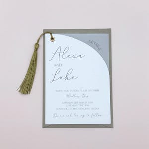 May include: A wedding invitation with a gray and brown envelope. The invitation is for Alexa and Luka's wedding on Saturday, March 21st, 2026. The ceremony will be held at Sunny Hill Court, Newquay, Treiaa.
