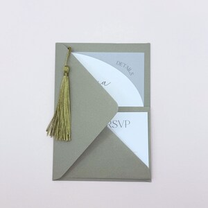 May include: A gray envelope with a gold tassel. The envelope has a white insert with the word "DETAILS" printed on it. The insert also has a white RSVP card.