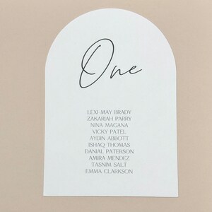 May include: White arch-shaped card with the word "One" written in black cursive. The card lists the names of ten guests: Lexi-May Brady, Zakariah Parry, Nina Magana, Vicky Patel, Aydin Abbott, Ishaq Thomas, Danial Paterson, Amira Mendez, Tasnim Salt, and Emma Clarkson.