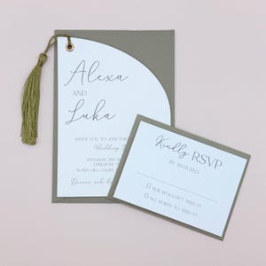 May include: A sage green wedding invitation with a white RSVP card. The invitation features a half-circle design with the names "Alexa and Luka" in cursive script. The RSVP card has the text "Kindly RSVP by 20.03.2023" and two options: "Yes, I wouldn't miss it!" and "No, sorry to miss it!"