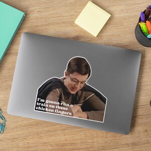 May include: A sticker featuring a man with brown hair and a black shirt. The man is looking down and smiling. The sticker has the text "I'm gonna run a train on these chicken fingers" in white letters.