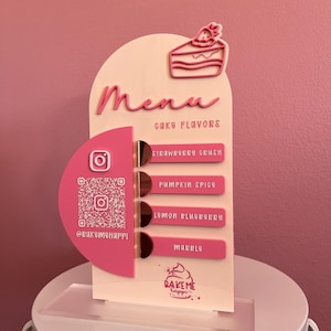 May include: A pink and white cake menu with a slice of cake graphic. The menu lists cake flavors: Strawberry Crush, Pumpkin Spice, Lemon Blueberry, and Marble. It includes a QR code and Instagram handle.
