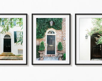 May include: Three framed prints of black front doors with white trim and green foliage. The doors are on different colored buildings, one white, one brick, and one white.