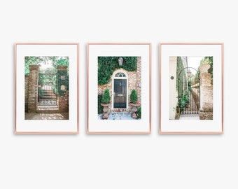 May include: Three framed prints of a brick building with a black door and a wrought iron gate. The door is surrounded by green ivy and the gate is in a brick archway. The prints are in rose gold frames.