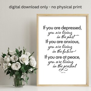 May include: A framed print with the quote "If you are depressed, you are living in the past. If you are anxious, you are living in the future. If you are at peace, you are living in the present." The print is in a light wood frame and includes the text "digital download only - no physical print."