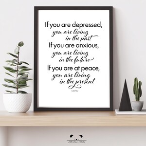 May include: A framed print with a white background and black text. The quote reads: "If you are depressed, you are living in the past. If you are anxious, you are living in the future. If you are at peace, you are living in the present." Signed by Lao Tzu.