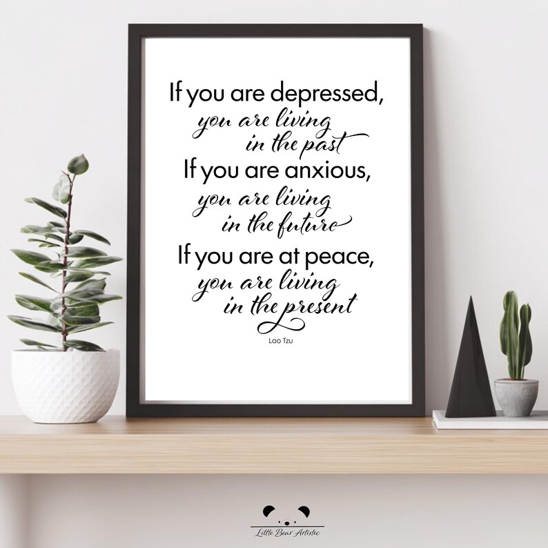 May include: A framed print with a white background and black text. The quote reads: "If you are depressed, you are living in the past. If you are anxious, you are living in the future. If you are at peace, you are living in the present." Signed by Lao Tzu.