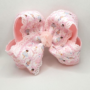 Puede incluir: Lazo grande para el pelo rosa con una cinta blanca con estampado de bailarina. El lazo tiene un ribete de encaje festoneado y un peque&ntilde;o lazo rosa en el centro. El lazo mide aproximadamente 15 cm de ancho.