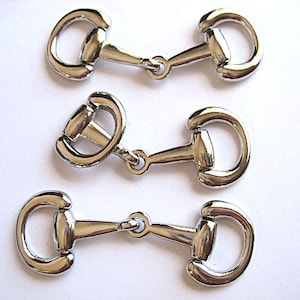 May include: Three silver-toned metal horse bit buckles. Each buckle has a round ring on one end and a D-shaped ring on the other end.