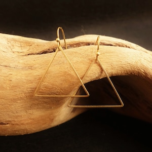 May include: A pair of gold triangle earrings with a simple, geometric design. The earrings are made of a thin wire and have a delicate, minimalist look.