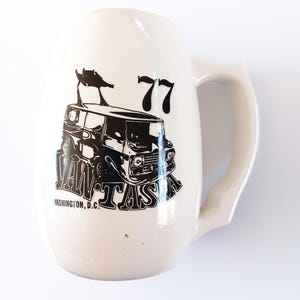 May include: White ceramic mug with a black and white illustration of a van with the text "VAW-TASA" and "77" on it. The text "WASHINGTON, D.C." is also printed on the mug.