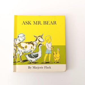 May include: A vintage children's book titled "Ask Mr. Bear" with a bright yellow cover. The cover features illustrations of farm animals and a child. The author's name, Marjorie Flack, is printed at the bottom.