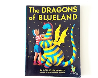 Könnte beinhalten: Ein Buchcover mit schwarzem Hintergrund und gelben Sternen. Der Titel lautet "The Dragons of Blueland" von Ruth Stiles Gannett, illustriert von Ruth Chrisman Gannett. Das Cover zeigt einen blau-gelb gestreiften Drachen mit rotem Kamm und einen Jungen in einem rot-weiß gestreiften Hemd.