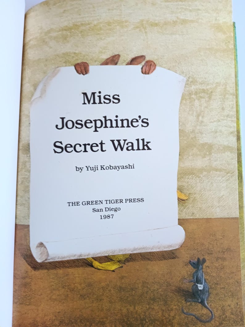 May include: Illustration from a children's book titled "Miss Josephine's Secret Walk" by Yuji Kobayashi. The book cover features a scroll held by brown hands, with a small mouse in the corner. Published by The Green Tiger Press in San Diego, 1987.