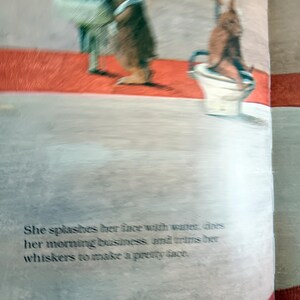 May include: Illustration from a children's book featuring two brown rabbits. One rabbit stands near a sink, while the other sits on a toilet. The text reads, "She splashes her face with water, does her morning business, and trims her whiskers to make a pretty face."