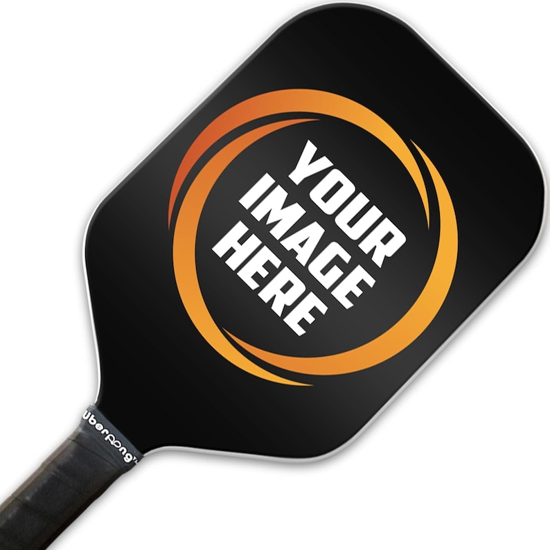May include: Black pickleball paddle with a white circle and the text "YOUR IMAGE HERE" in a yellow and orange swirl design.