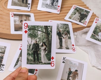 Puede incluir: Un juego de cartas de juego con fotos de boda. Las cartas son blancas con símbolos de diamantes y picas rojos. Las fotos muestran a una pareja en varios entornos, incluyendo un bosque, una iglesia y un campo.