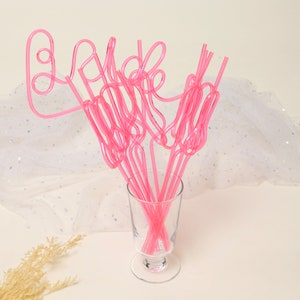May include: Pink plastic straws shaped to spell out the word "bride" in a glass vase. The straws are a fun and festive addition to a bridal shower or wedding.