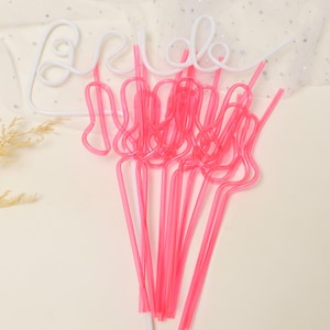 May include: A set of pink plastic straws shaped like a hand with the word "bride" written in white on a white background.