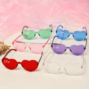 Puede incluir: Seis pares de gafas de sol con forma de coraz&oacute;n con nombres personalizados: Kley, Watson, Amelia, Nikki, Olivia y Nikki. Las gafas de sol son de varios colores, incluidos rojo, rosa, verde, morado, azul y transparente.