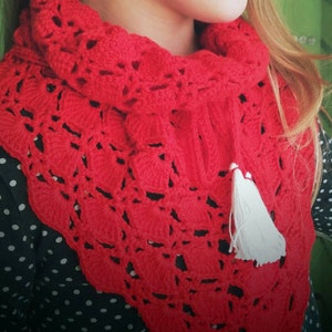 May include: A red crocheted scarf with a white tassel. The scarf is made with a delicate openwork pattern.