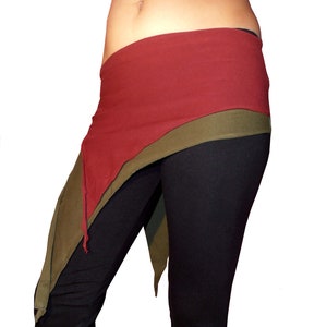 Può includere: Una gonna a portafoglio in tessuto rosso e verde con forma triangolare. La gonna è legata in vita e ha un design lungo e fluido.