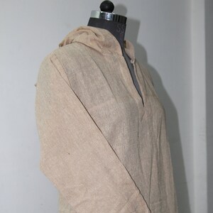 Op de afbeelding: Een beige langarm shirt met capuchon, V-hals en een losse pasvorm.