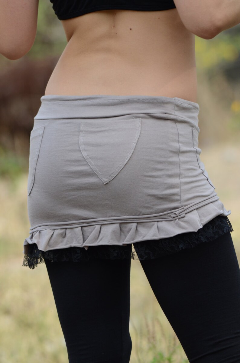 May include: A gray skirt with a ruffle hem and a heart-shaped pocket. The skirt is paired with black leggings.
