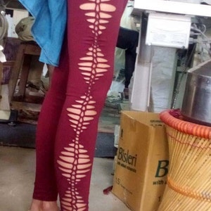 Op de afbeelding: Bordeauxrode leggings met een uniek uitgesneden ontwerp aan de zijkant. De uitsnijdingen hebben de vorm van een ruitpatroon.