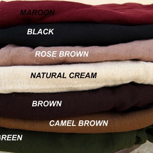 Op de afbeelding: Een stapel stofstalen in verschillende kleuren, waaronder maroen, zwart, roosbruin, naturel cr&egrave;me, bruin, camelbruin en groen.