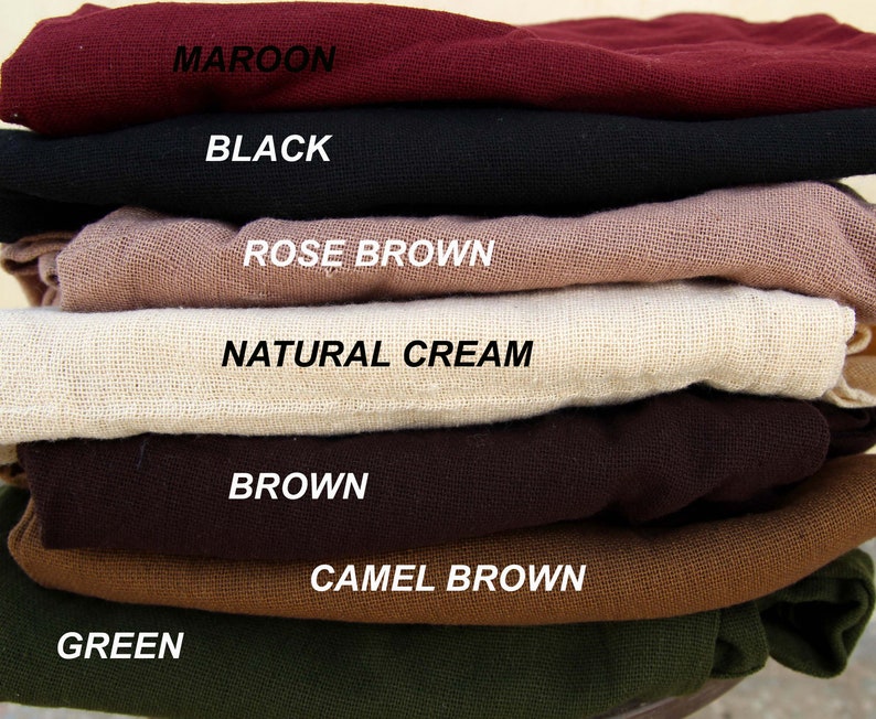 Op de afbeelding: Een stapel stofstalen in verschillende kleuren, waaronder maroen, zwart, roosbruin, naturel cr&egrave;me, bruin, camelbruin en groen.