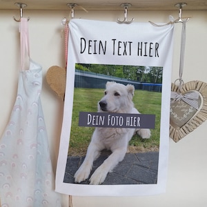 Könnte beinhalten: Weißes Küchentuch mit dem Text "Dein Text Hier" und "Dein Foto Hier" darauf gedruckt. Das Handtuch zeigt ein Foto eines weißen Hundes, der auf einer gepflasterten Fläche liegt.