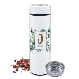 Könnte beinhalten: Weiße Thermosflasche aus Edelstahl mit einem grünen und goldenen Blumendesign und dem Buchstaben "J" in einem goldenen Quadrat mit dem Namen "Jessica" darunter. Die Flasche hat einen eingebauten Tee-Infuser.