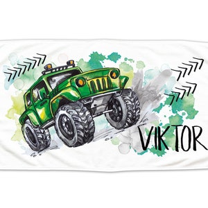 Könnte beinhalten: Ein weißes Handtuch mit einem grünen Cartoon-Jeep, der durch einen Aquarellhintergrund fährt. Der Jeep hat schwarze Räder und ein schwarzes Dachgepäckträger. Der Hintergrund ist ein Mix aus grünen, blauen und grauen Aquarellspritzer. Der Name "VIKTOR" ist in Schwarz unter dem Jeep geschrieben.